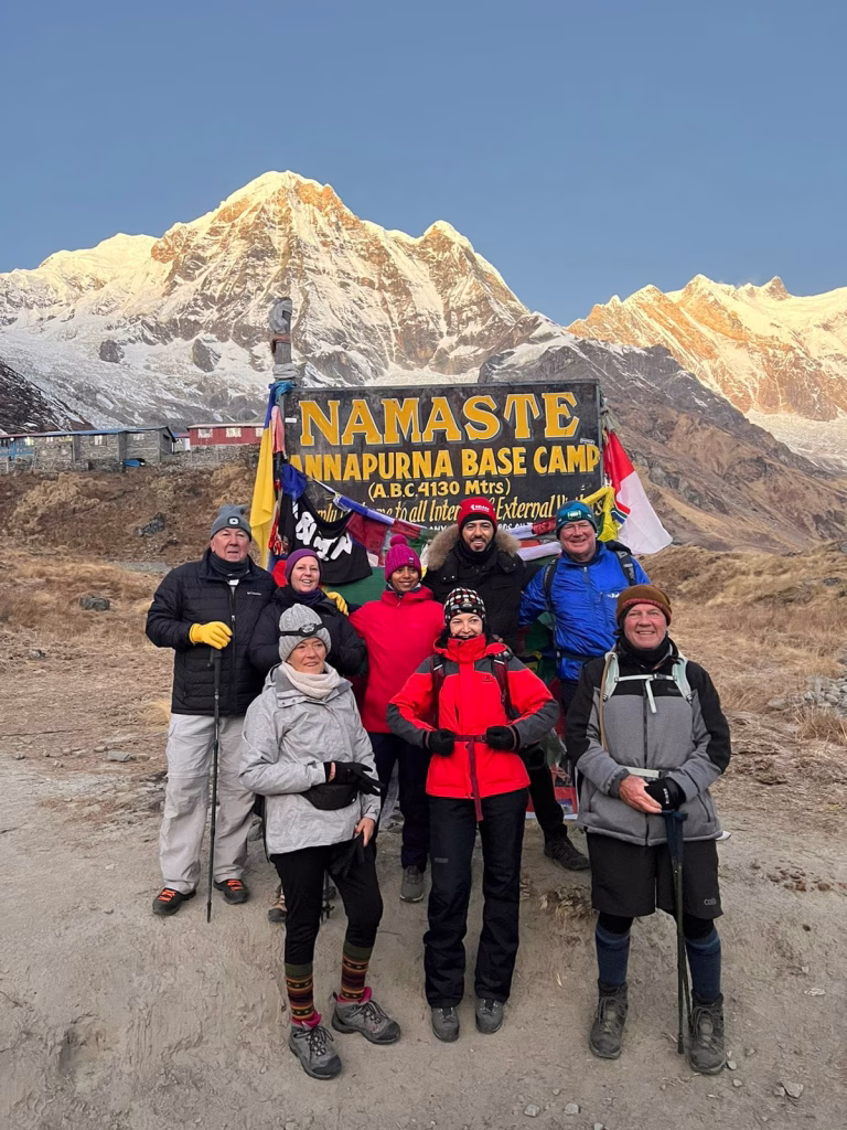 Group of people posing in front of a board saying Annapurna Base Camp