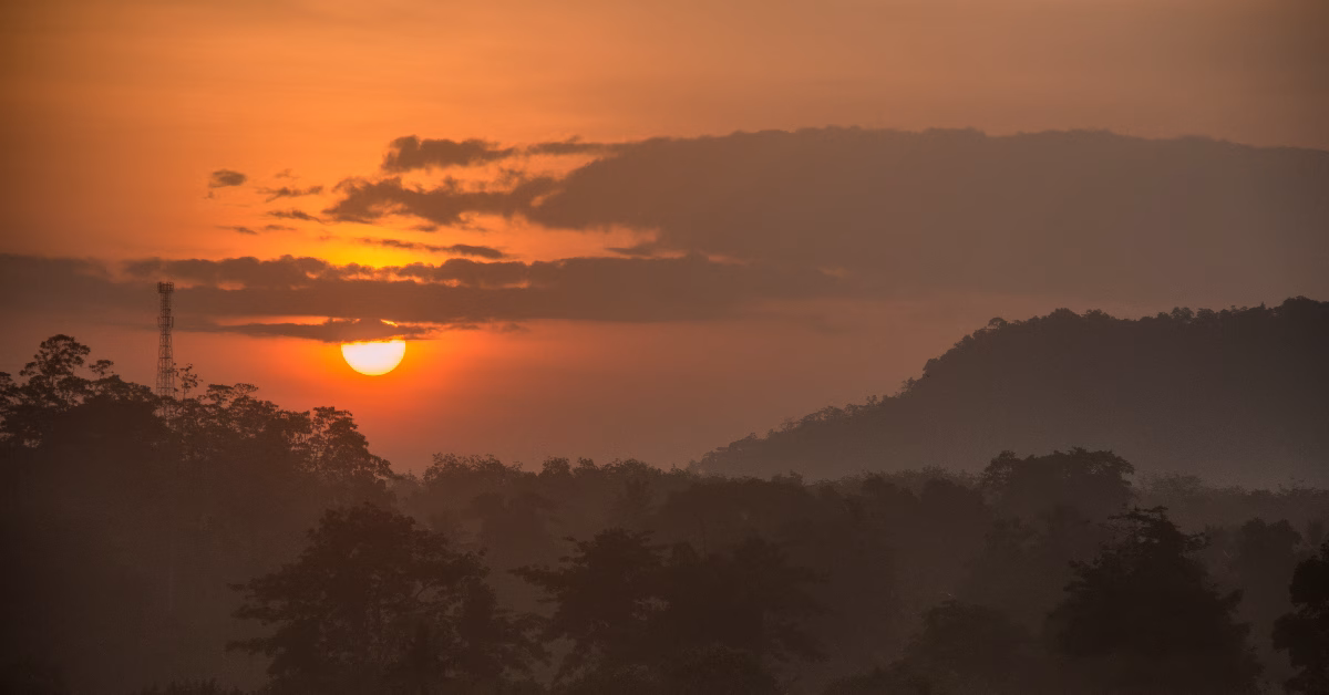 Golden sunrise over misty hills with a forest